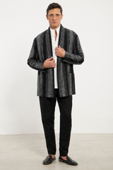 Man wearing a gray patterned blazer over a white shirt with black pants and shoes on a white background