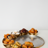 Assorted dried fruits and pastries on a metal tray with a white background