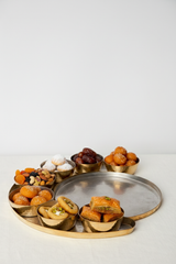 Assorted dried fruits and pastries on a metal tray with a white background