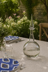 Clear glass decanter on a table with floral background