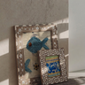 Decorative frames with fish designs on a textured wall.
