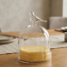 Glass container with a bird on top on a wooden table
