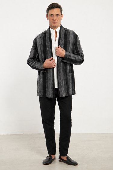 Man wearing a gray patterned blazer over a white shirt with black pants and shoes on a white background