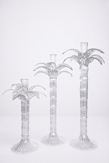 Set of three clear palm tree-shaped candle holders on a white background