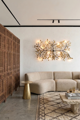 Modern living room with a beige sofa, decorative wall light fixture, and wooden side table.